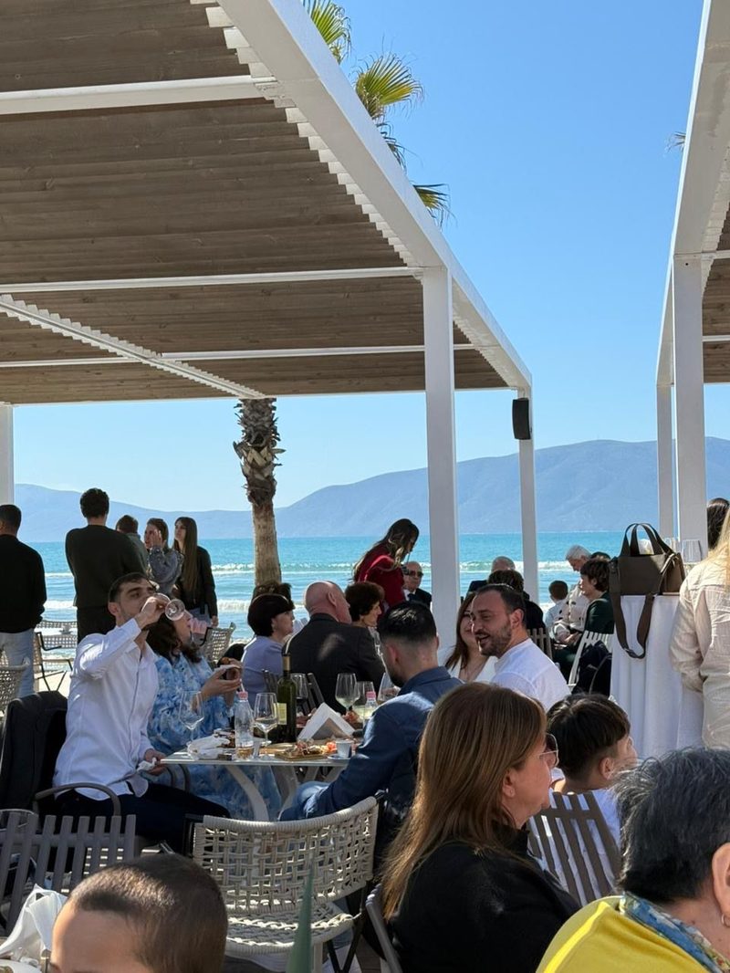 Guests dining on the outdoor terrace with turquoise sea and mountain views